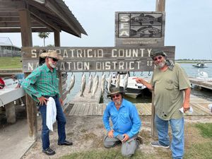 Three anglers pose with their catch on a stringer at San Patricio County Navigation District fishing dock.