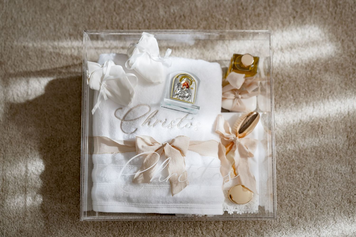 Luxury baptism gift box with white embroidered blanket, religious patch, and satin ribbon bow in acrylic case.