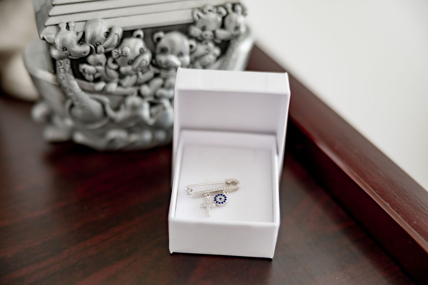 Silver ring with blue evil eye charm displayed in a white jewelry gift box.