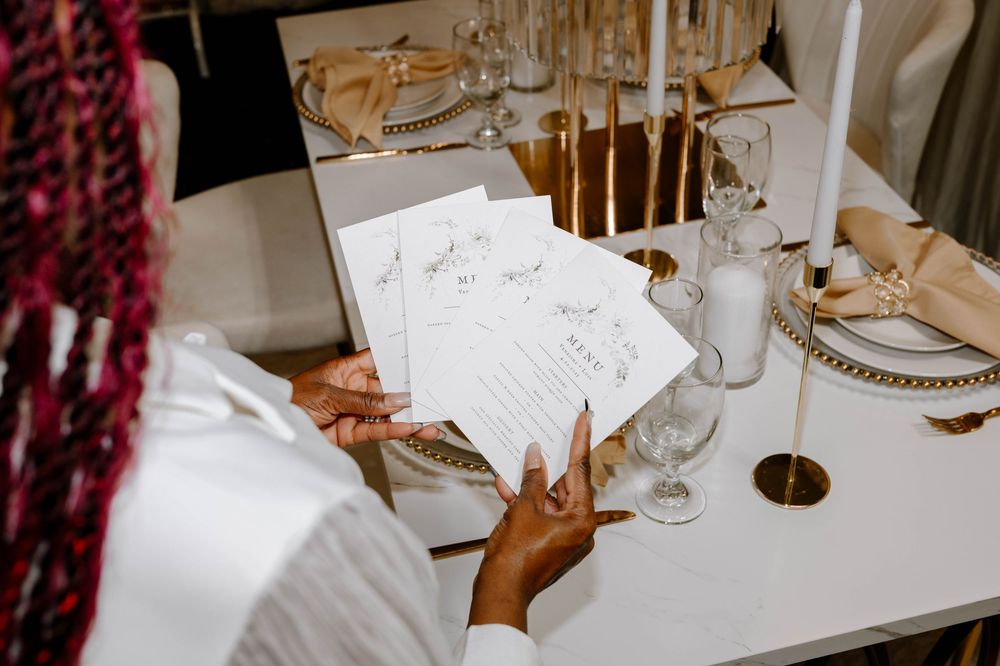 Woman reviewing wedding menu cards at a elegantly decorated table with gold candles.