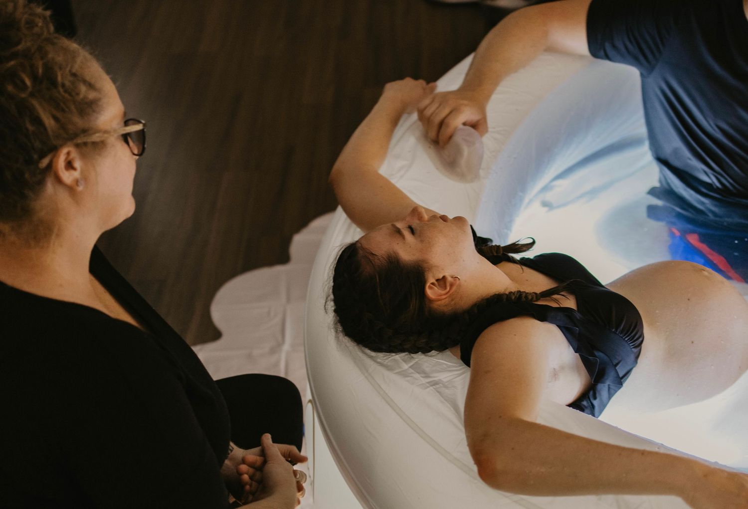 woman giving birth in a tub in her living room home birth photographer