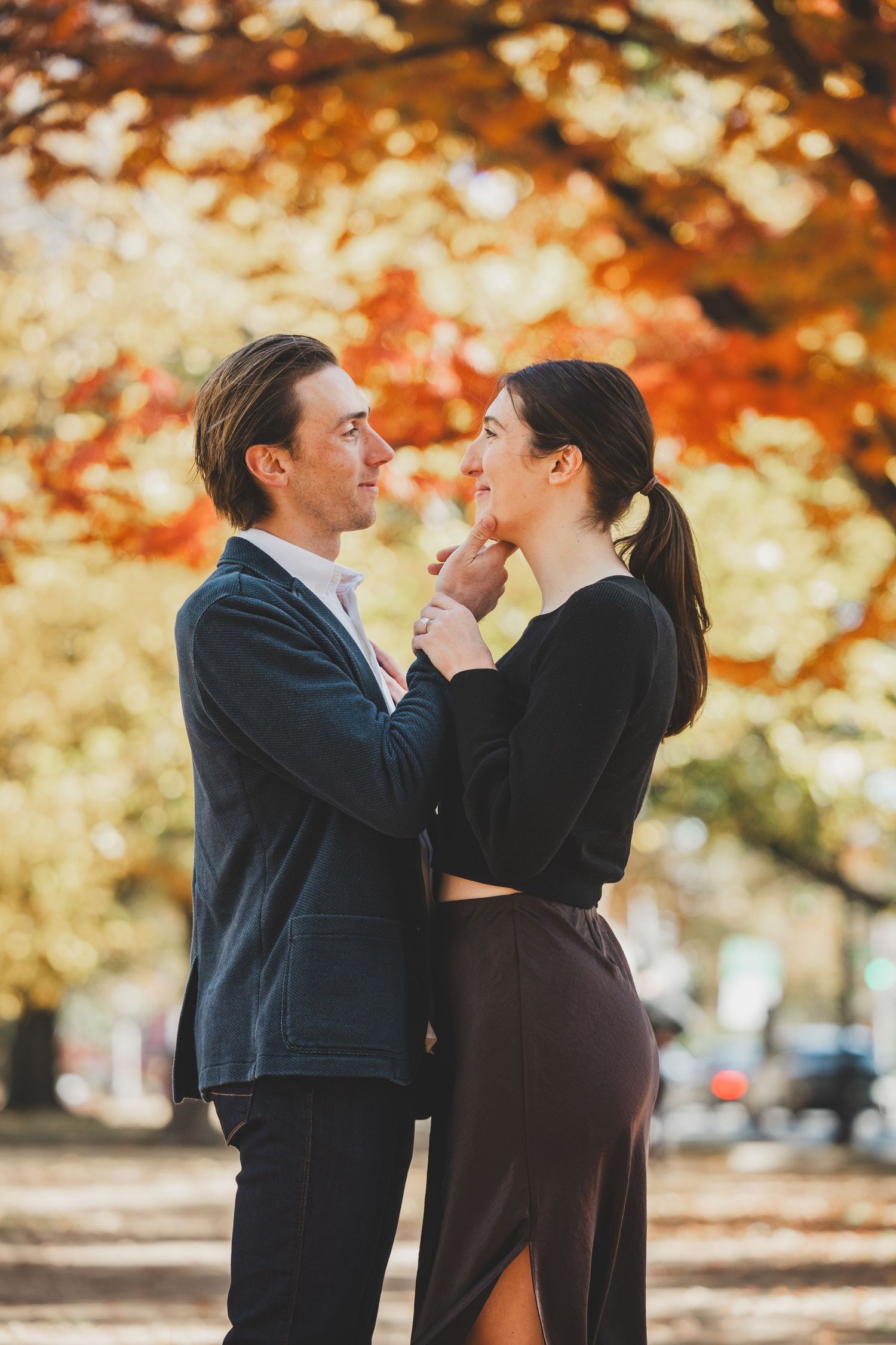 Romantic couple embracing in autumn park with colorful fall foliage in warm orange and red tones at Lincoln Park in DC