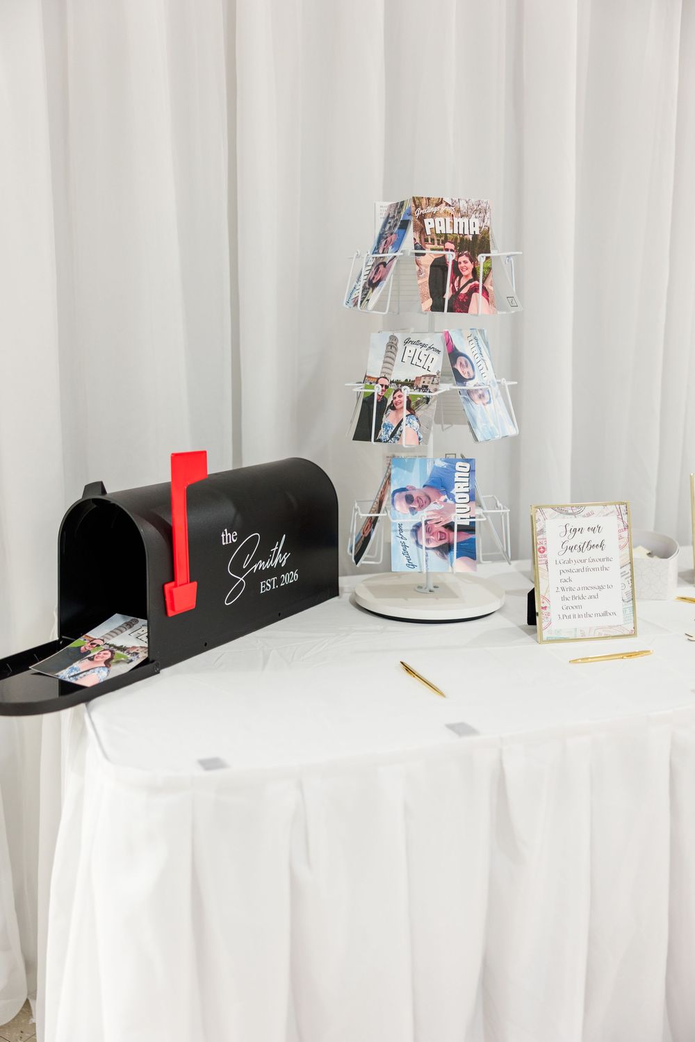 Wedding card table with black Smith mailbox, rotating card display, and elegant white tablecloth setup.