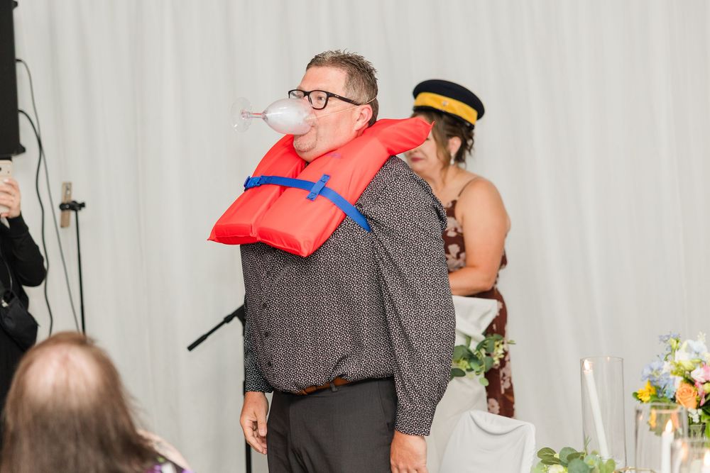 Wedding guest wearing red life jacket costume with bubble gum at fun reception photo booth activity.