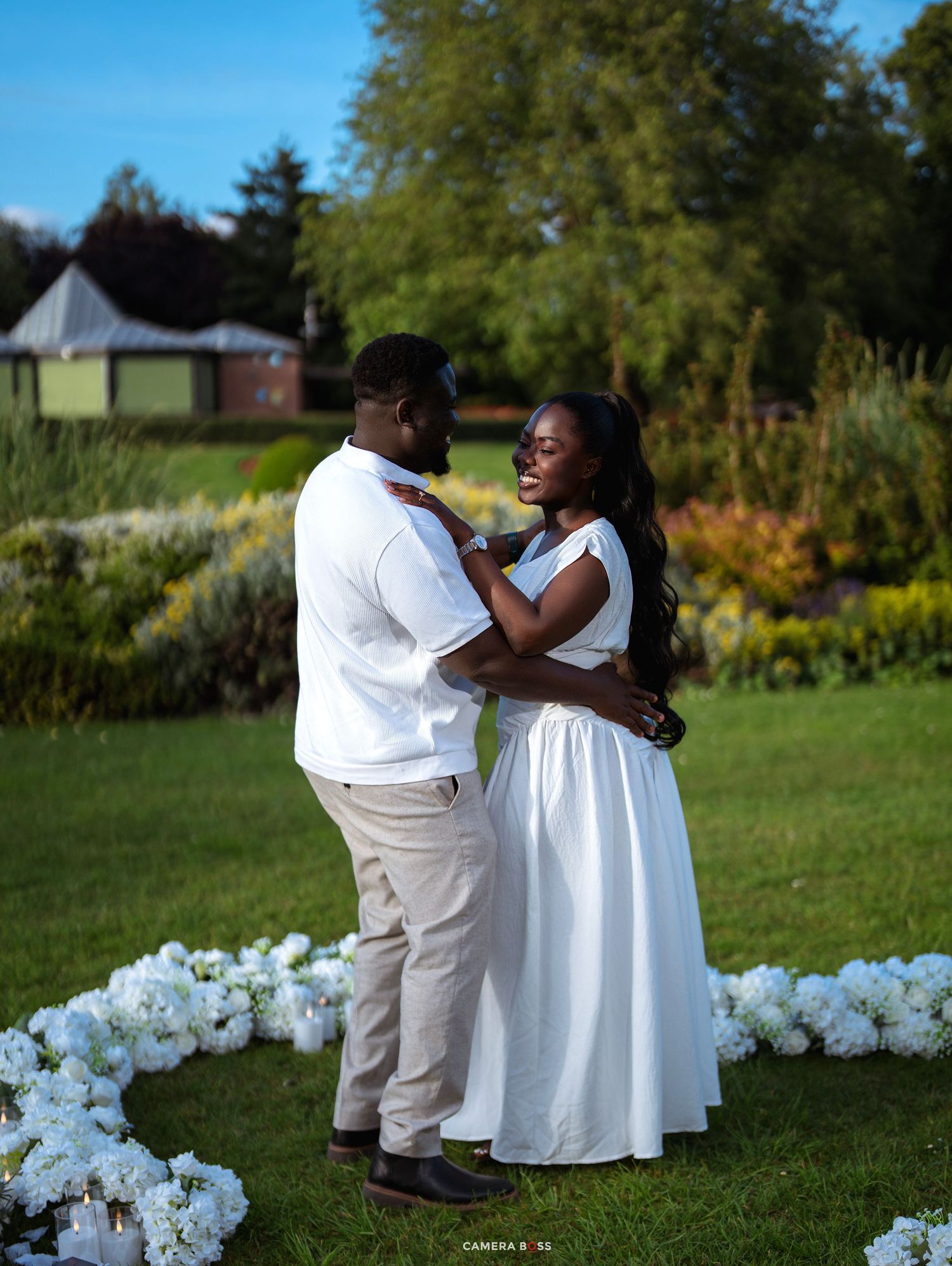 Couple in matching white outfits sharing a romantic moment in a lush garden surrounded by white hydrangeas.