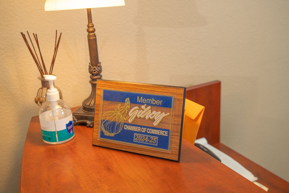 Gilroy Chamber of Commerce member plaque displayed on wooden desk with hand sanitizer and reed diffuser.