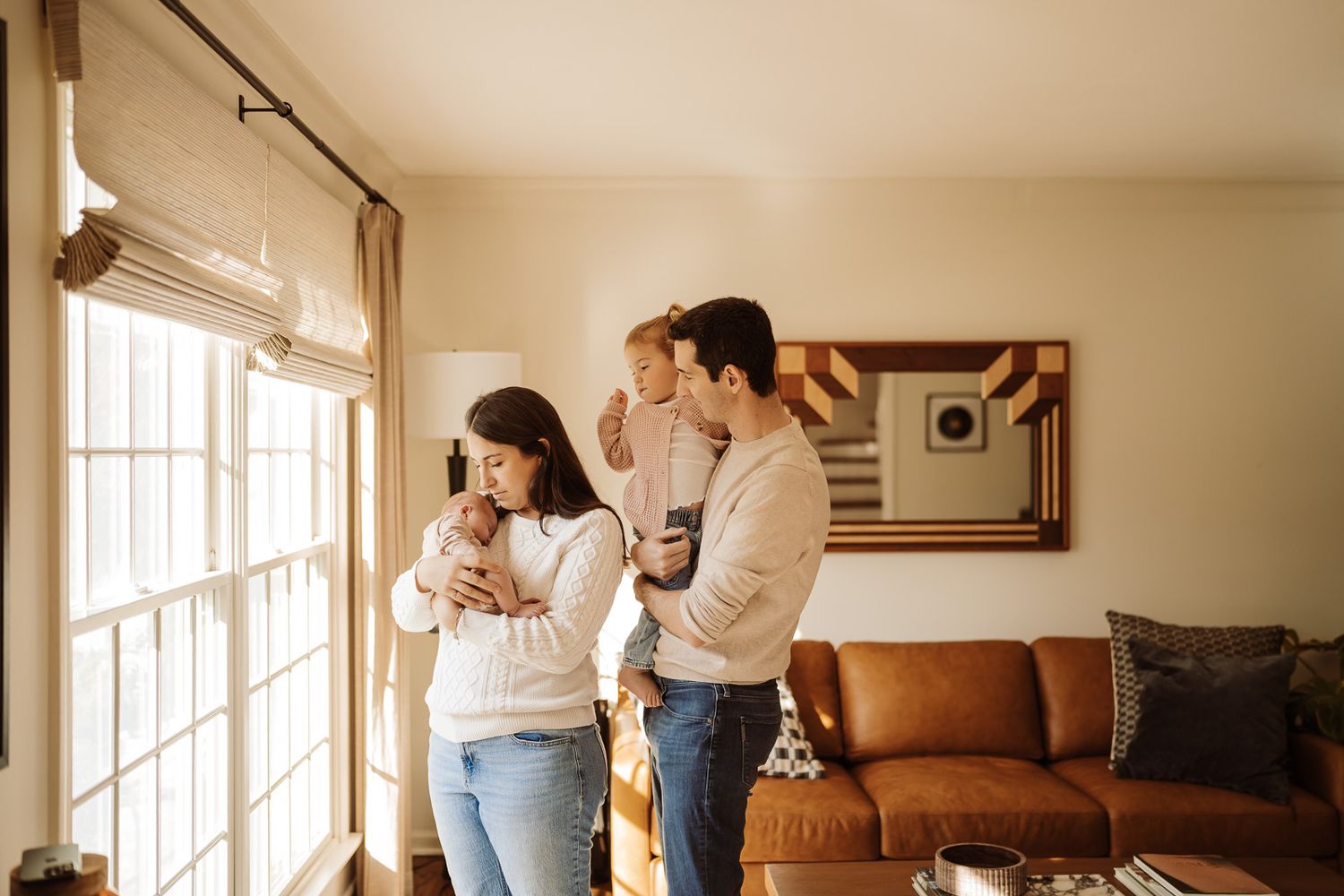Family moments shows people interacting and embracing in a warmly lit living room setting during newborn session in Barrington.