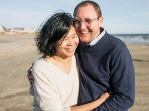 Happy couple embracing and smiling on a sandy beach on a sunny day.