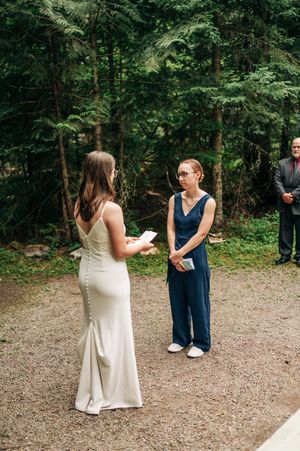 Two women exchange wedding vows in an outdoor forest ceremony.