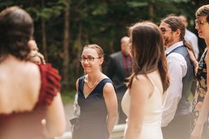 Wedding guests mingling outdoors in natural light at a forest wedding celebration.
