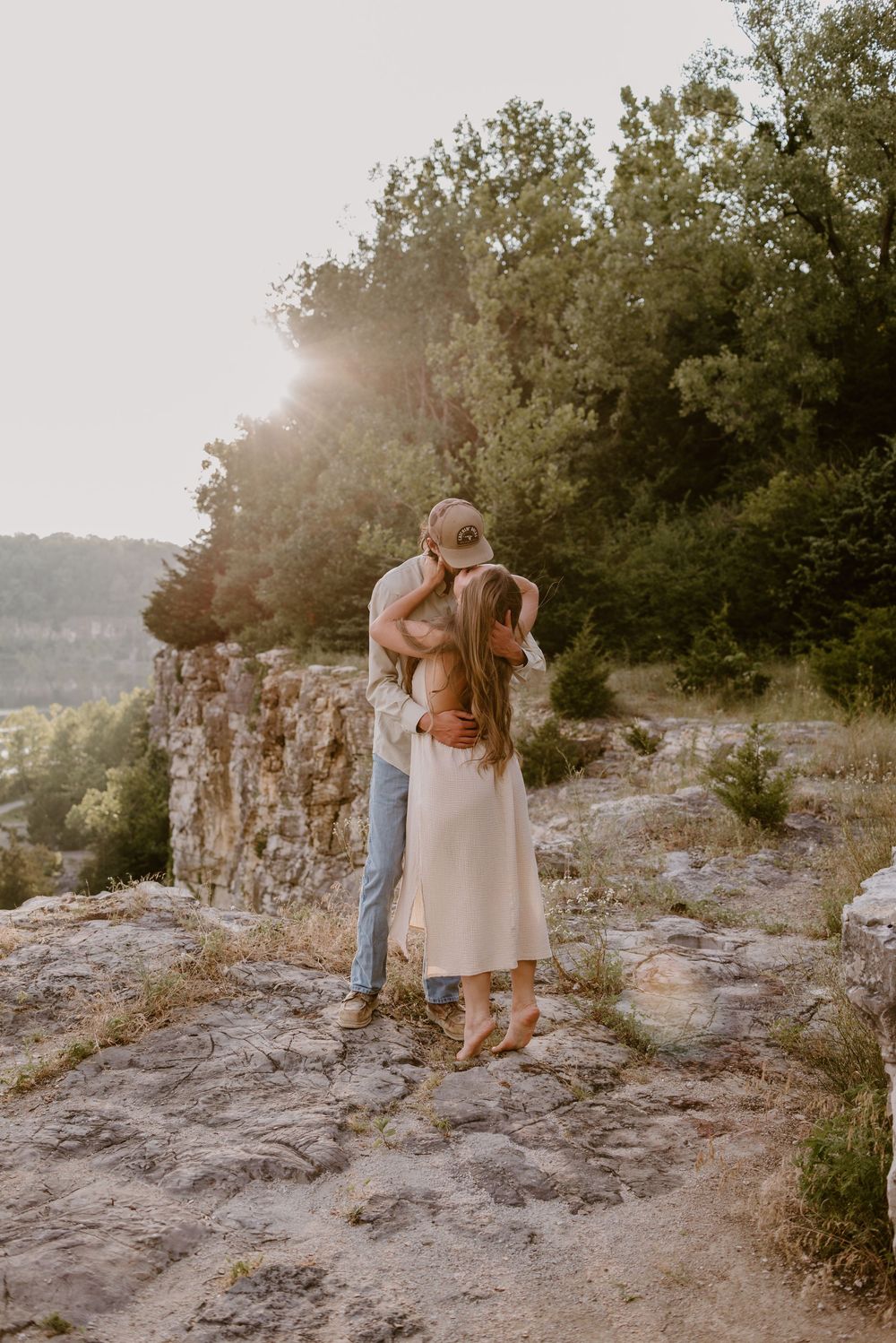 A couple shares tender moments on rocky terrain during sunset.