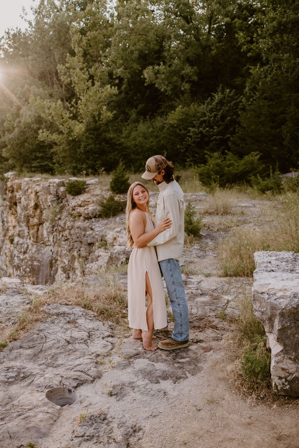 A couple shares intimate moments on rocky terrain during sunset.