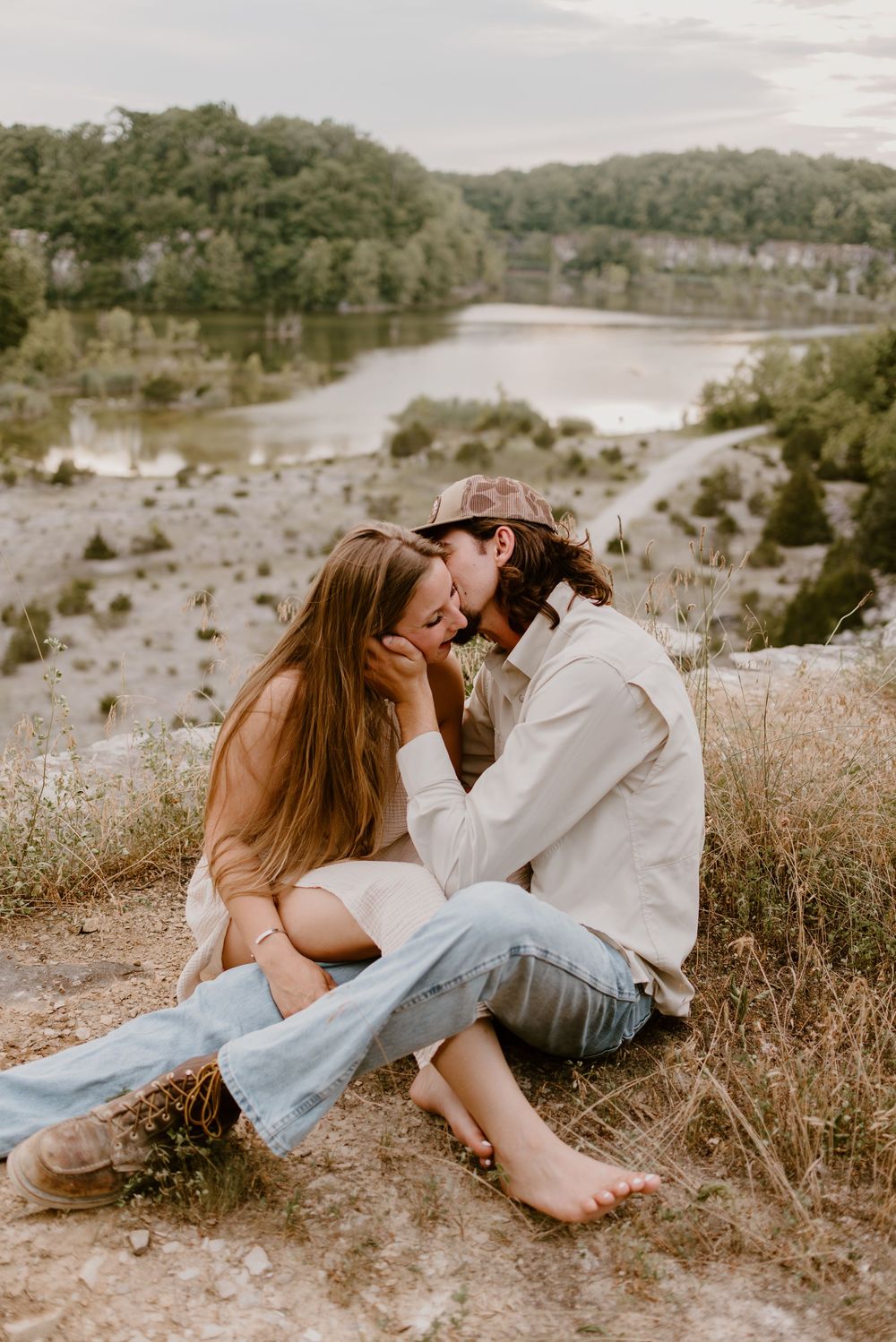 A couple reclines on dry grass during a romantic sunset photoshoot.