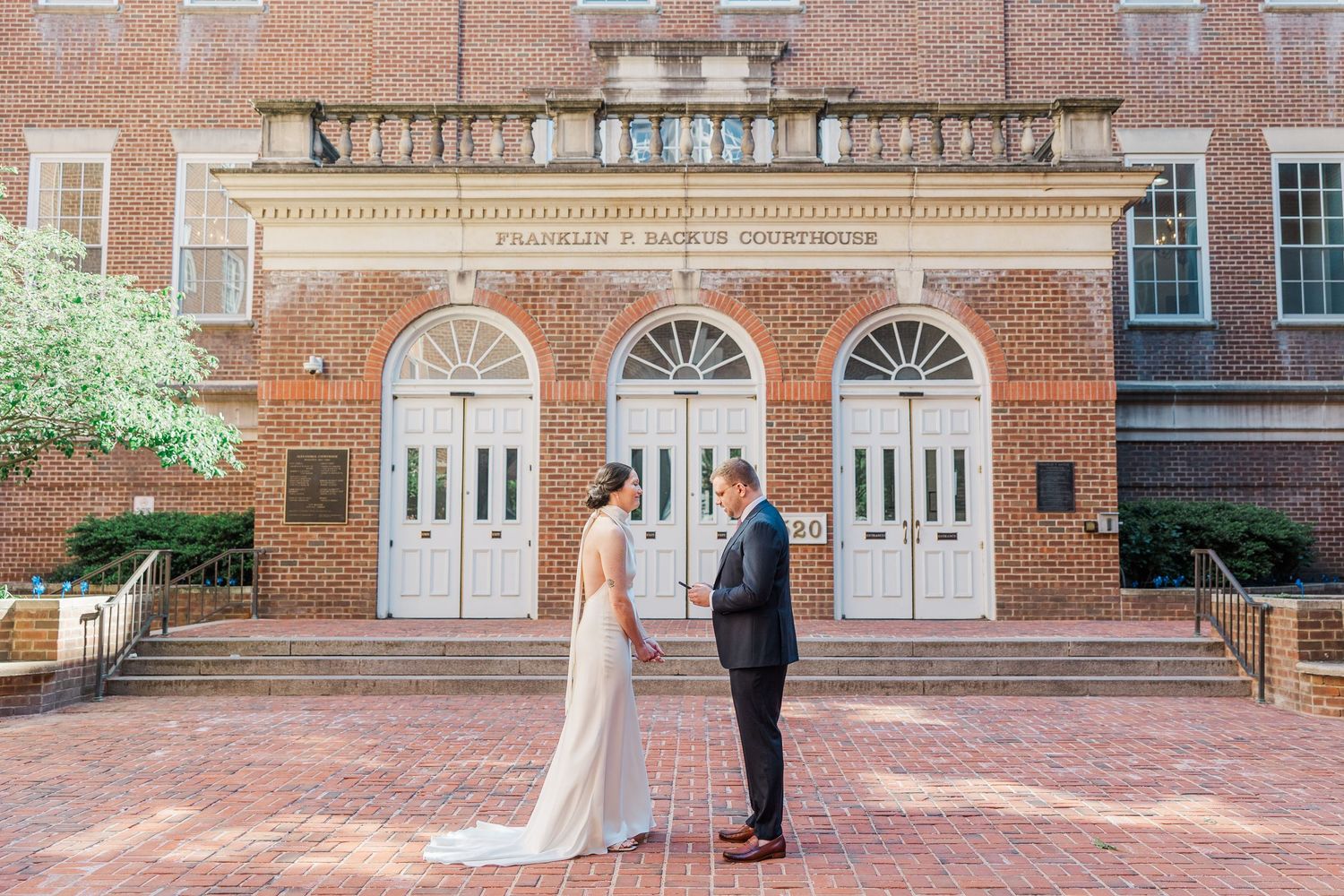Bride and groom share a first look moment outside a historic brick courthouse on their wedding day.