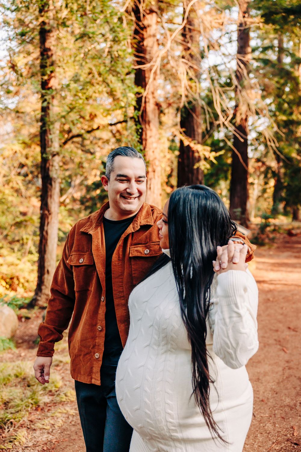 Happy couple sharing a moment on a forest trail surrounded by autumn trees.