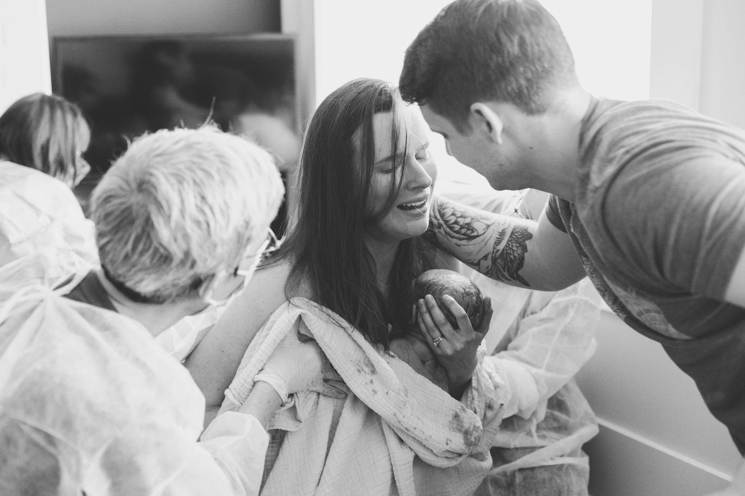 Mom is holding baby after birth on her chest, dad and midwife are supporting. Home birth in Ottawa.
