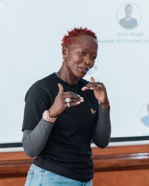 Woman with red hair gestures while presenting at a business conference.