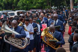 Brass band leads procession at formal outdoor ceremony in matching blue suits.