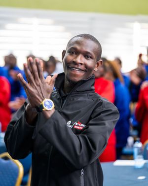 Enthusiastic man in black jacket clapping at a corporate sporting event.