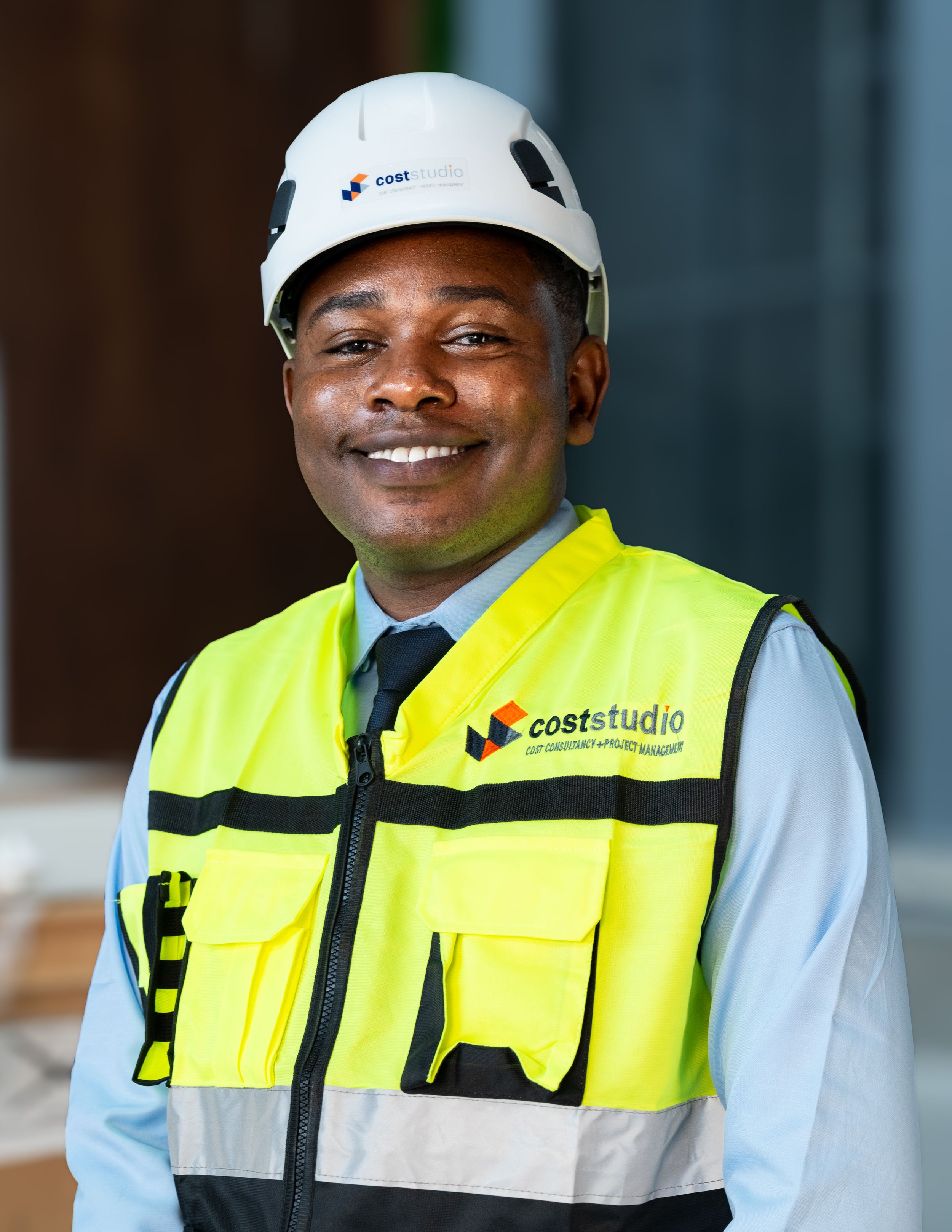 Smiling construction professional wearing a hard hat and high-visibility vest with CostStudio branding.