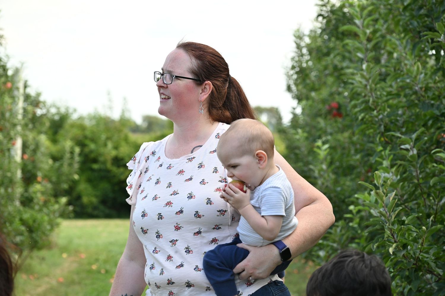 Mother carrying her young child outdoors during a family outing.