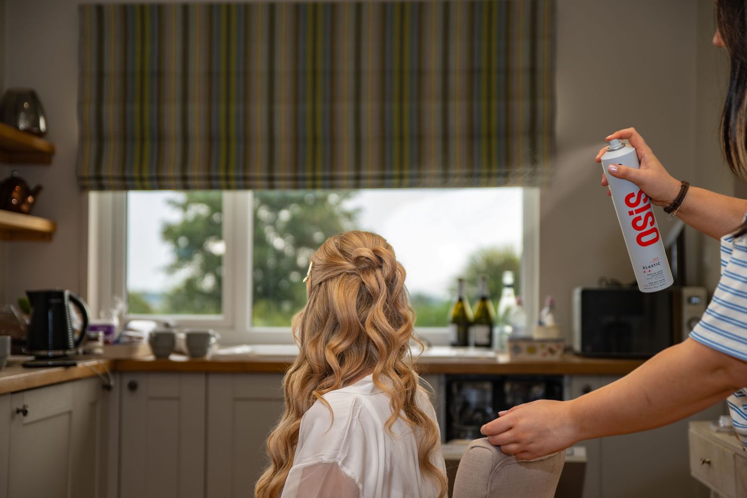 Hairstylist applying hairspray to the bride whilst she is getting ready for her wedding day. Sheffield, Yorkshire, Lincolnshire, UK