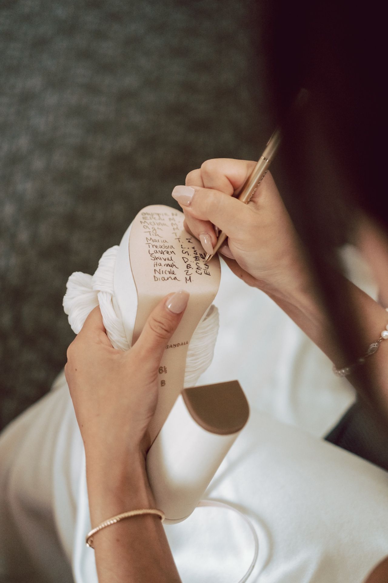 Bride writes names on wedding shoe sole, a cherished bridal tradition for good luck.
