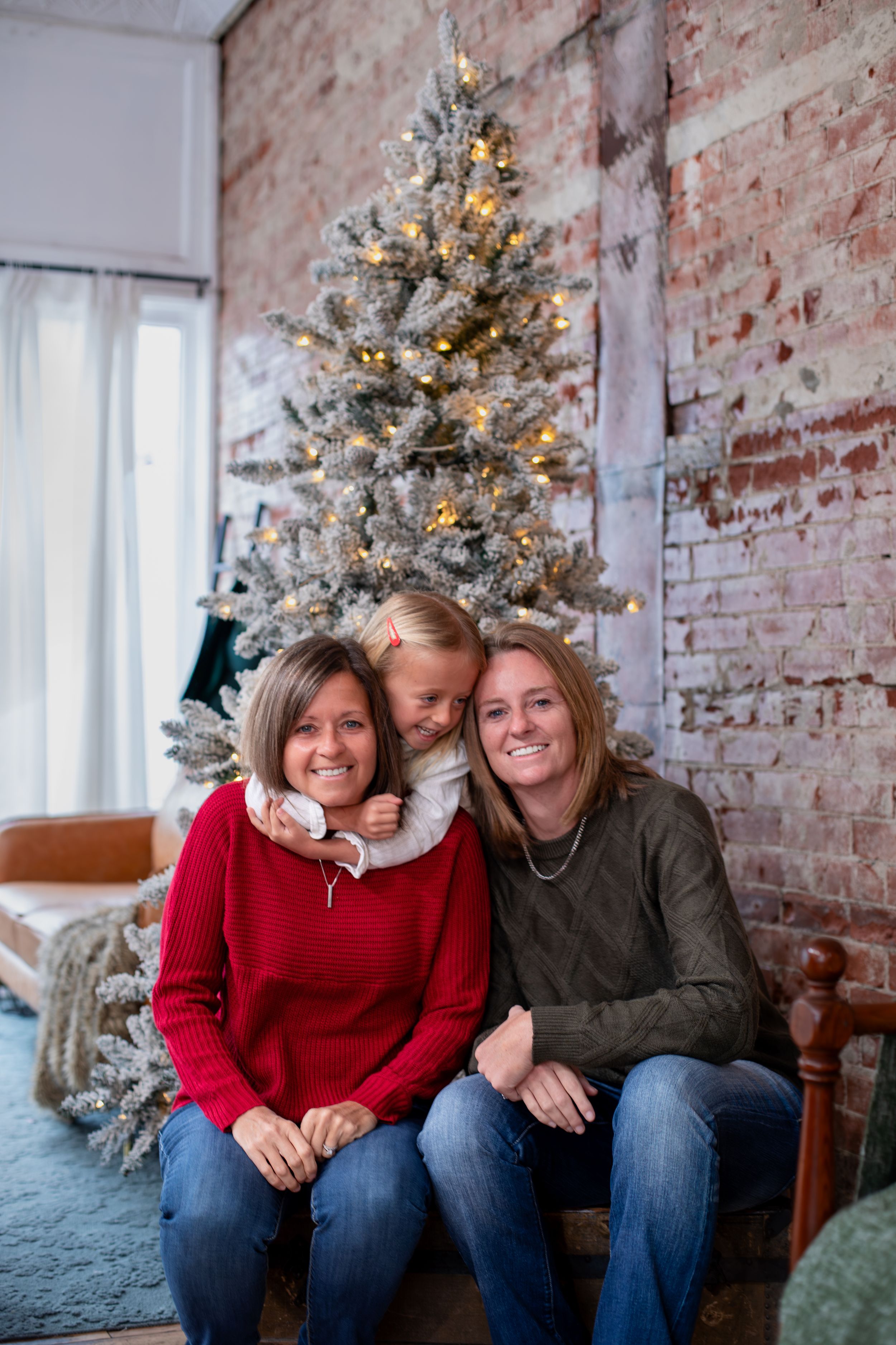 LGBTQ+ same-sex couple and daughter celebrating Christmas during a 2026 Cincinnati dog-friendly studio mini session with a local photographe
