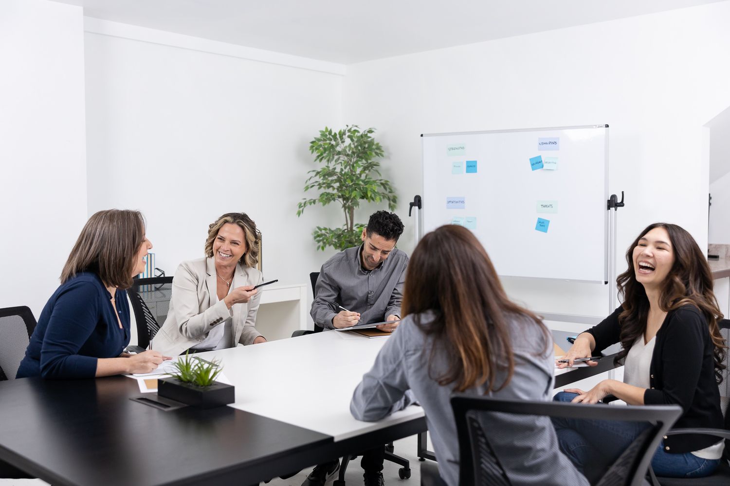 female business corporate coach working with group of 3 women and 1 man all laughing and smiling together in Bellevue, WA