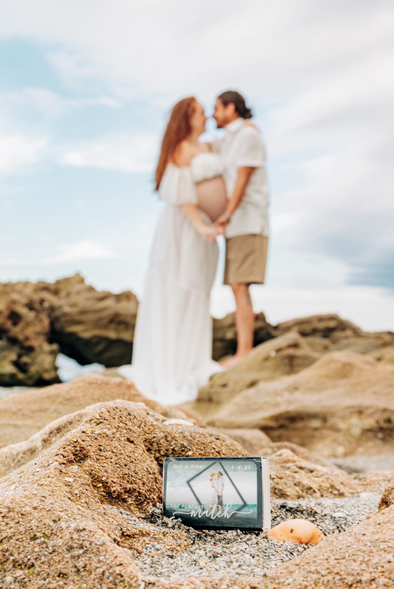 Maternity photographer Palm Beach County portrait of an expecting couple with their framed love story on the rocks at Coral Cove Beach in Ju