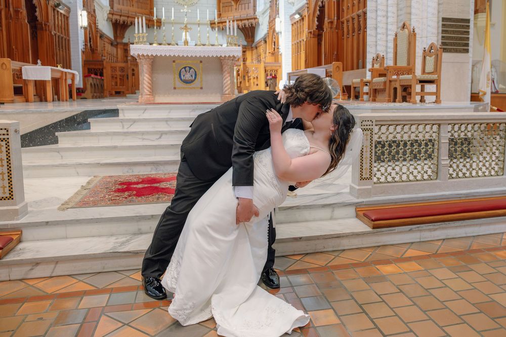 Bride and groom share a romantic dip kiss at the church altar on their wedding day.