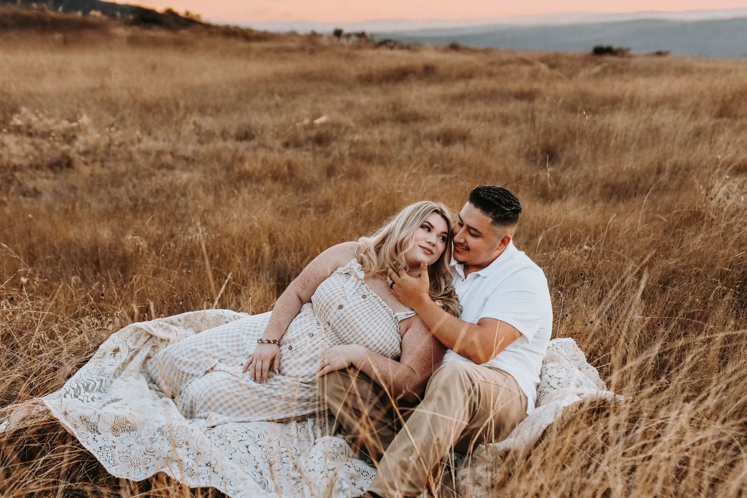 a couple lays in a golden field of grass at sunset overlooking lake grapevine