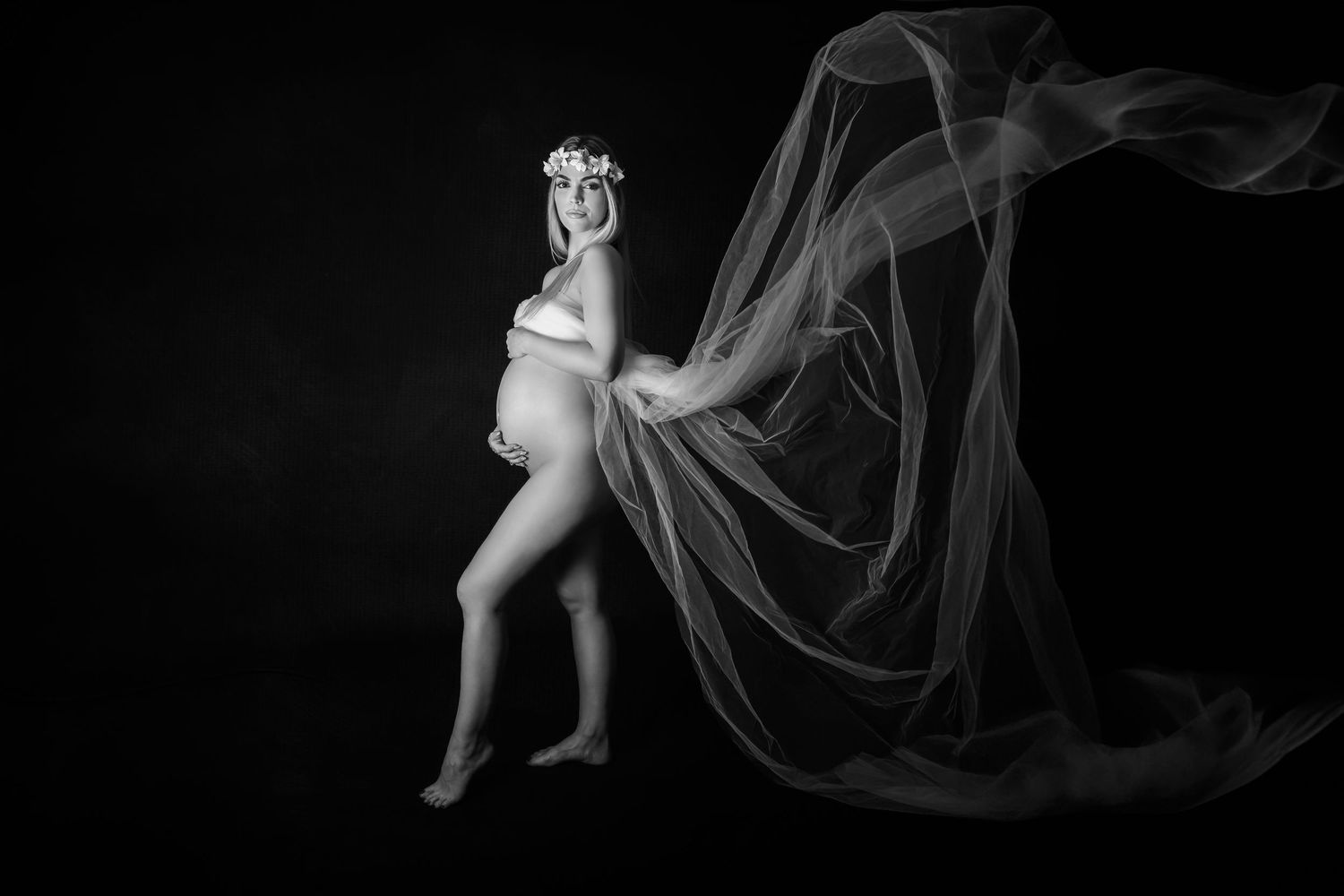pregnant lady in front of white background covered with white flying material