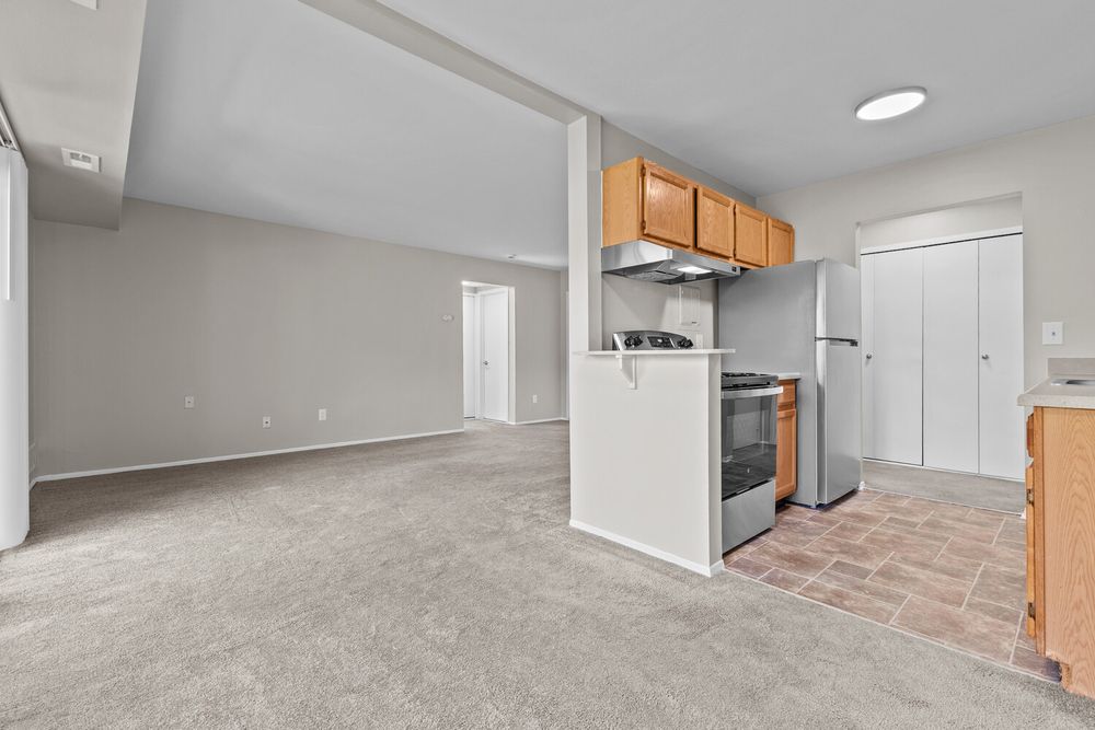 Open-concept kitchen with oak cabinets, gas range, tile flooring, and spacious carpeted living area.