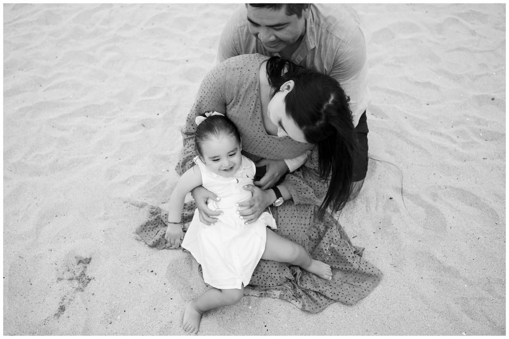 Black and white family portrait on a Punta Mita beach with parents and baby girl, candid family photography Riviera Nayarit.