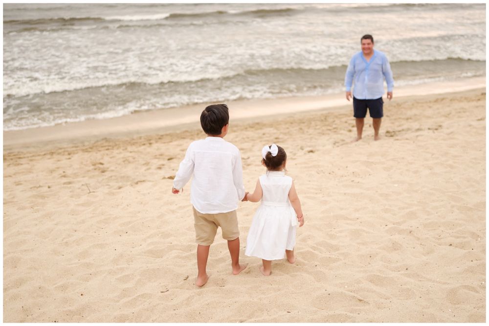 Siblings walking toward their father on a Punta Mita beach with ocean waves, candid family photography Riviera Nayarit.