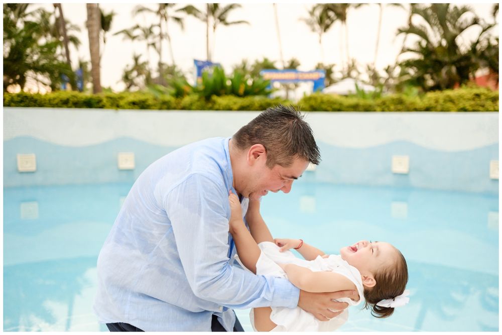 Father holding his baby near a Punta Mita resort pool with palm trees, candid family photography Riviera Nayarit.