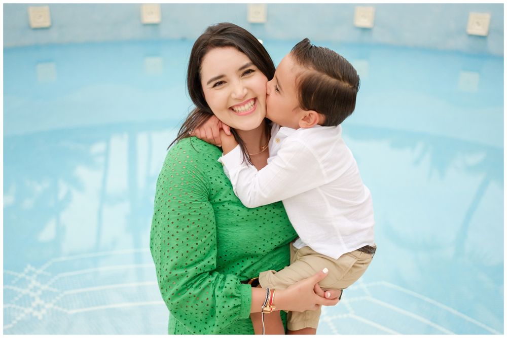 Son kissing his mother by a Punta Mita resort pool, candid family photography Riviera Nayarit.