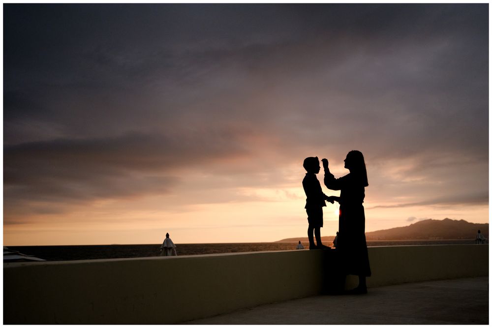 Mother and child silhouette at sunset in Puerto Vallarta, Mexico with dramatic sky, candid family photography Riviera Nayarit.