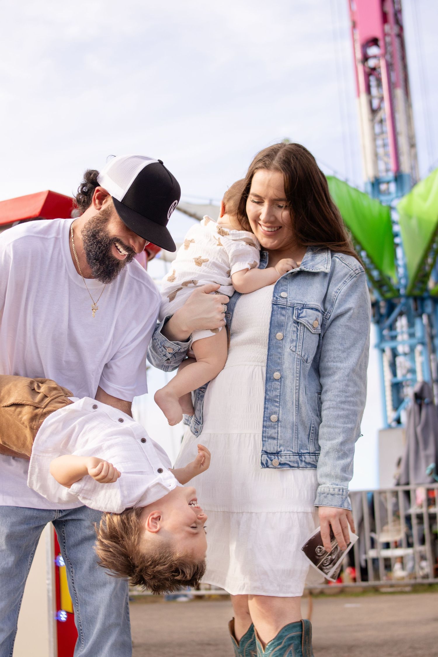 Mom and dad laughing with children at the fair.