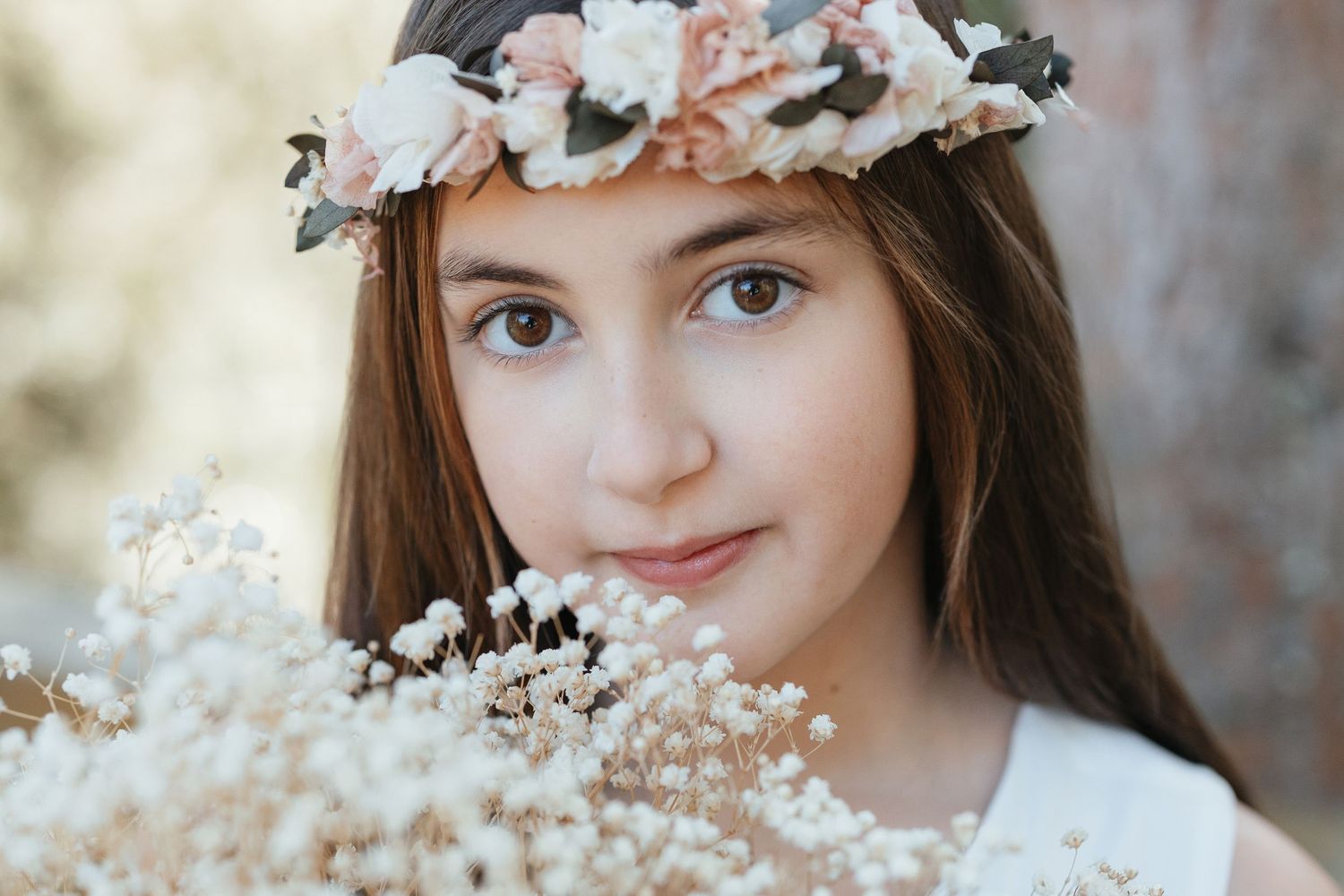 Young girl wearing a floral crown holding white baby's breath flowers, portrait photo.