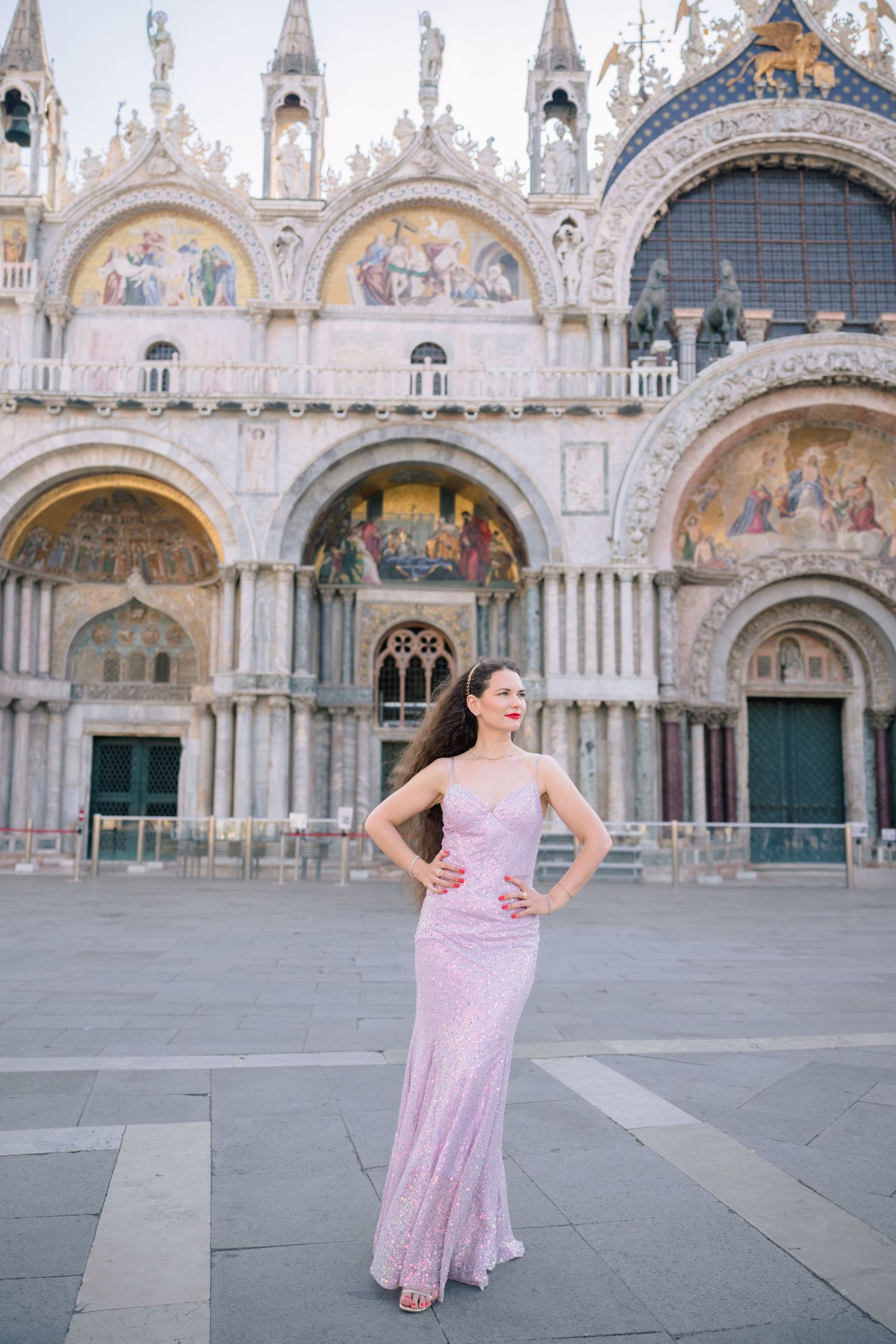 Woman in pink gown poses at St. Mark's Basilica, Venice, Italy.