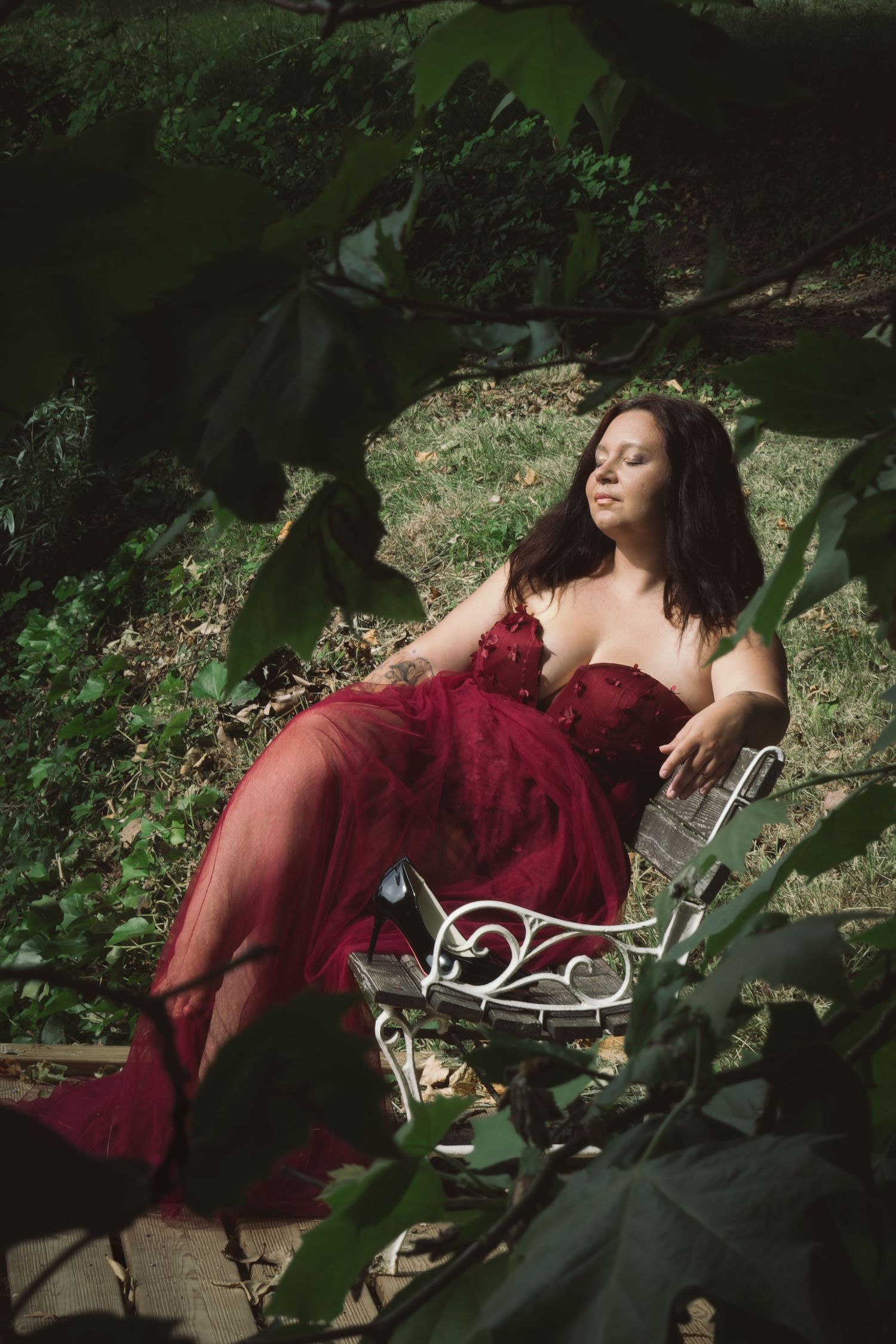 Portrait féminin dans un jardin luxuriant, baigné par une lumière naturelle contrastée.