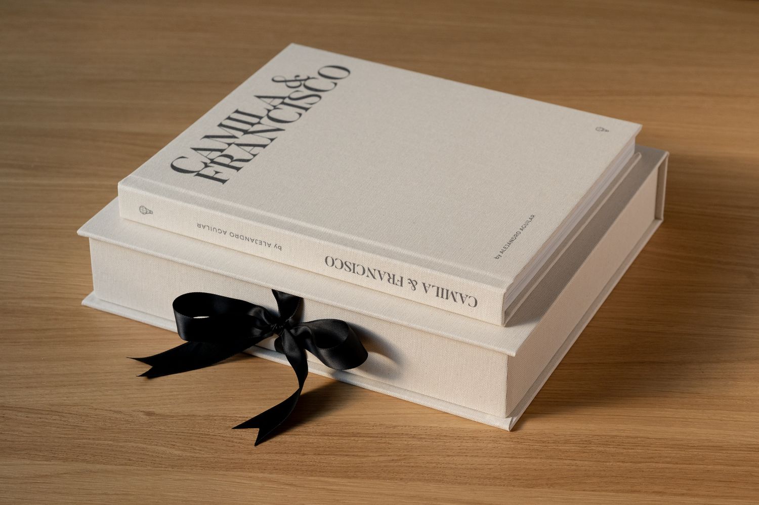 Elegant white wedding photo book with black ribbon bow, personalized with names Camila and Francisco.