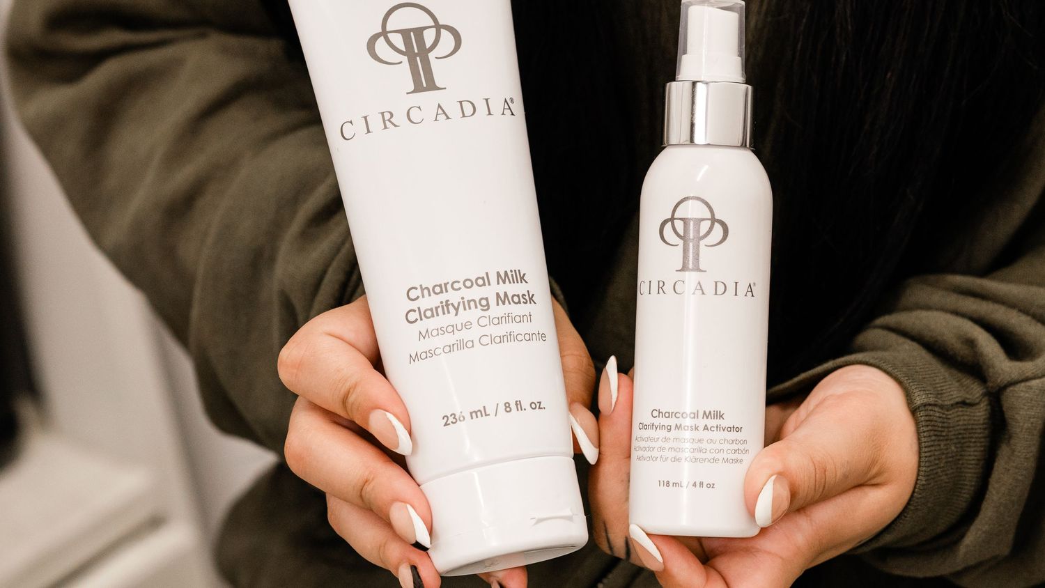Person holding Circadia Charcoal Milk Clarifying Mask and Cherry Milk Cleanser skincare products.