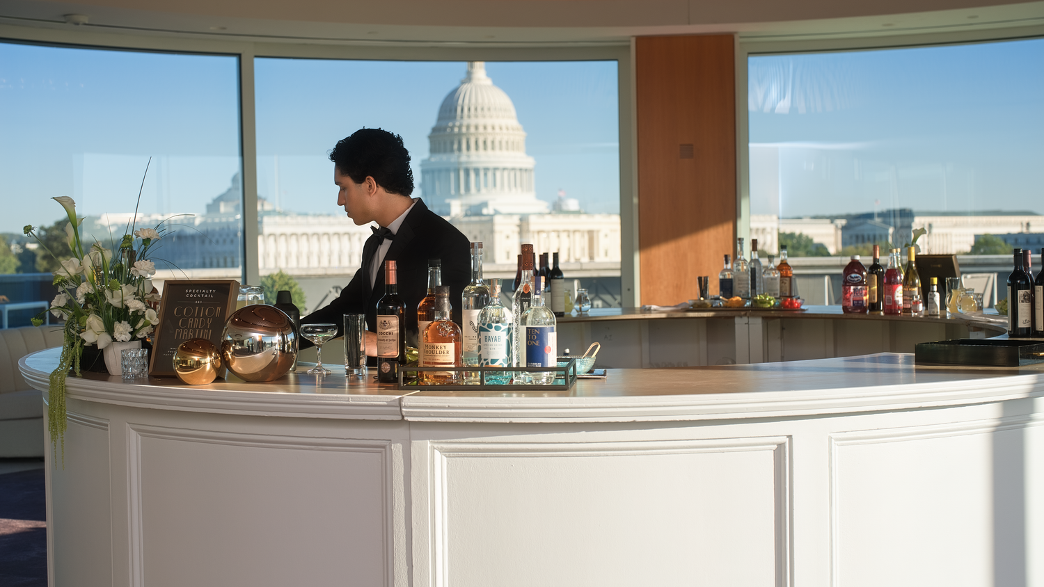A curved indoor bar at 101 Constitution with the U.S. Capitol visible through the windows.