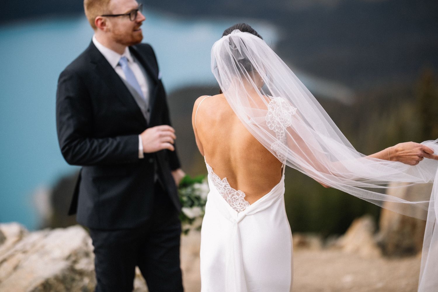 Groom watching his bride's veil blow at Peyto Lake, Lake Louise wedding