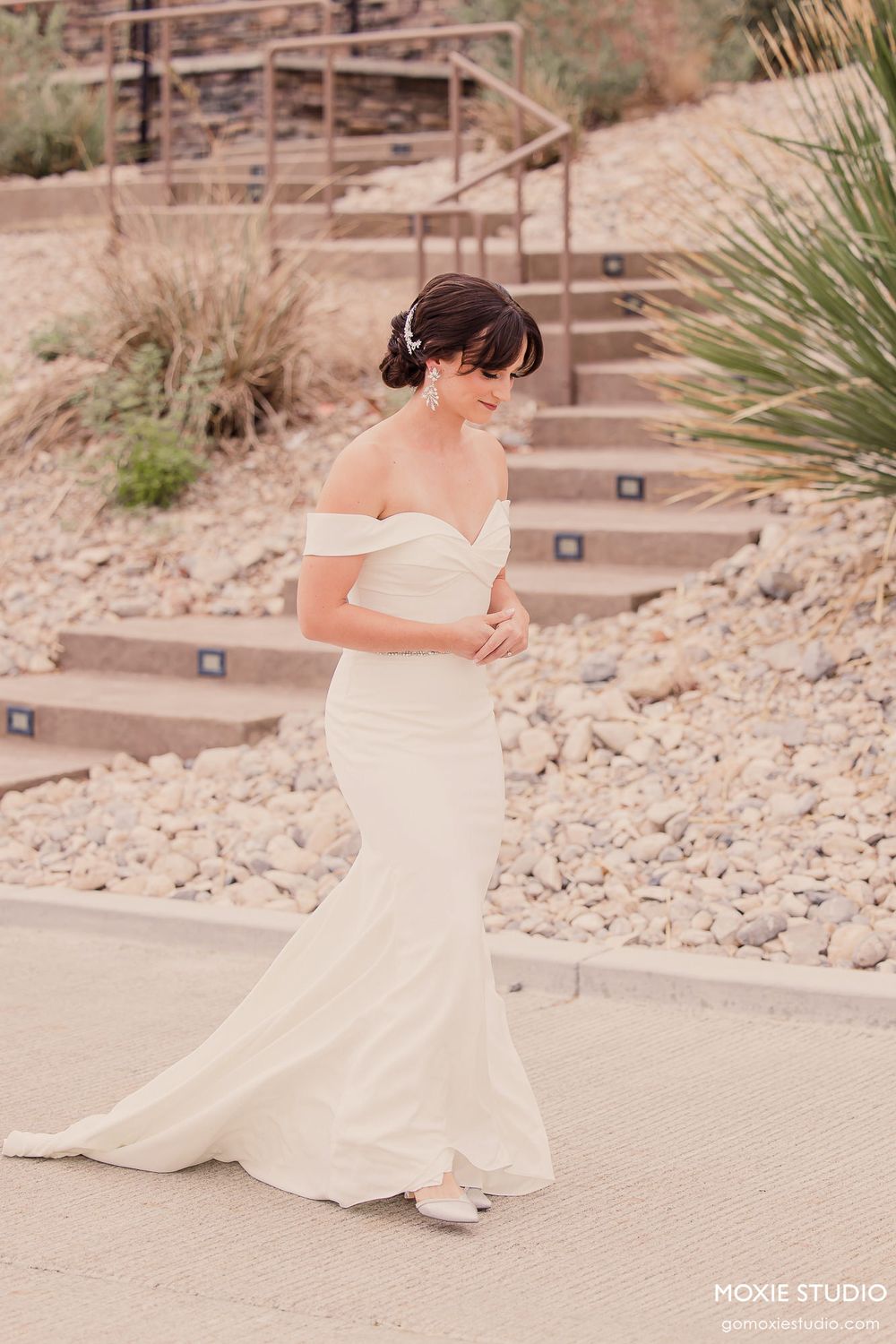 White wedding dress flowing gracefully on stone steps in a desert setting.
