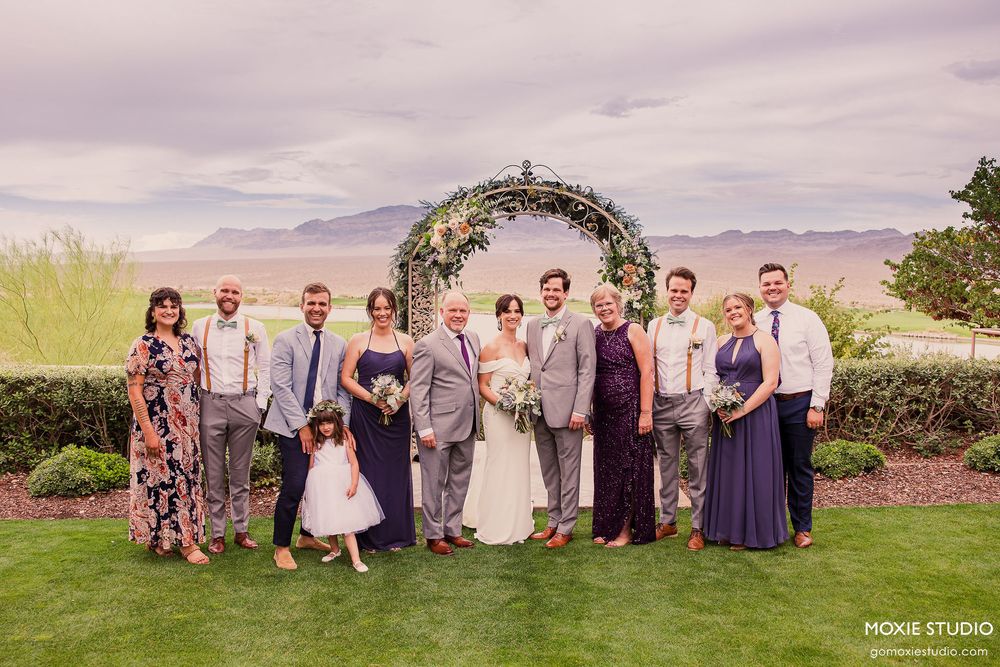 Wedding party poses together on a scenic mountain overlook with dramatic cloudy skies in the background.