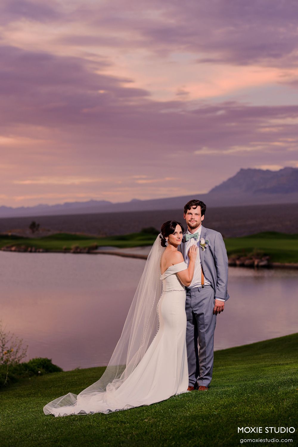 Elegant wedding portraits against a stunning purple sunset sky overlooking a serene lake.